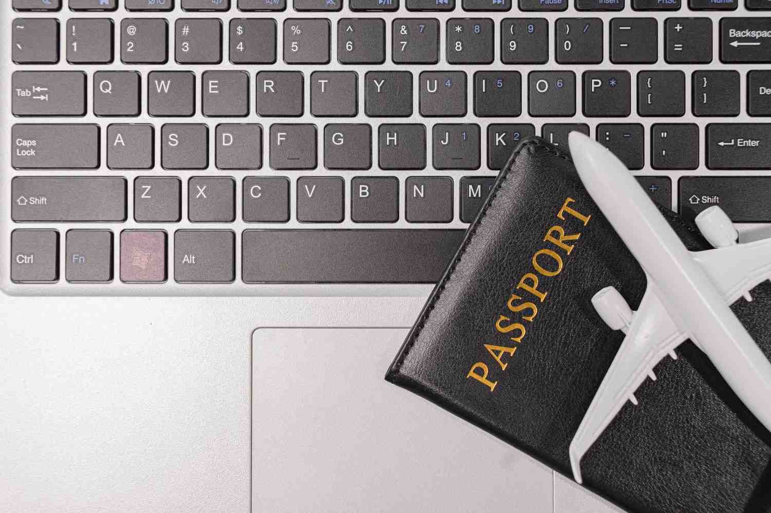 A Passport And A Airplane Miniature Lying On A Laptop