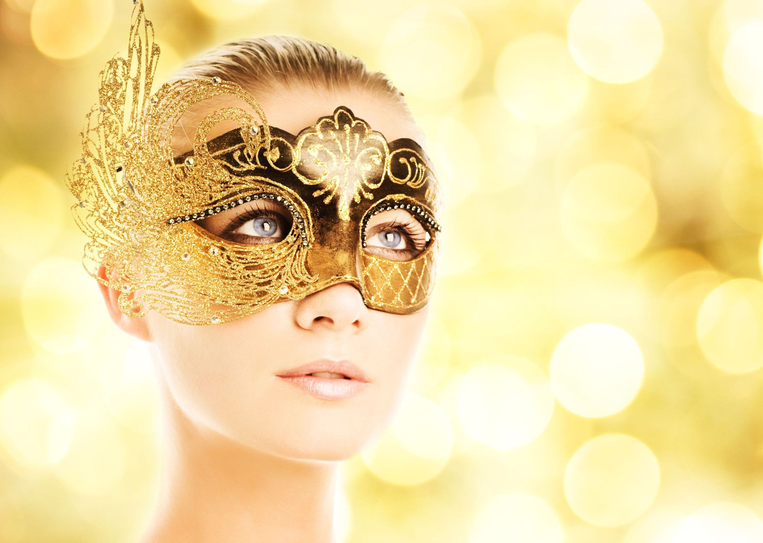 A woman wears a Golden Mask in a sparkling background