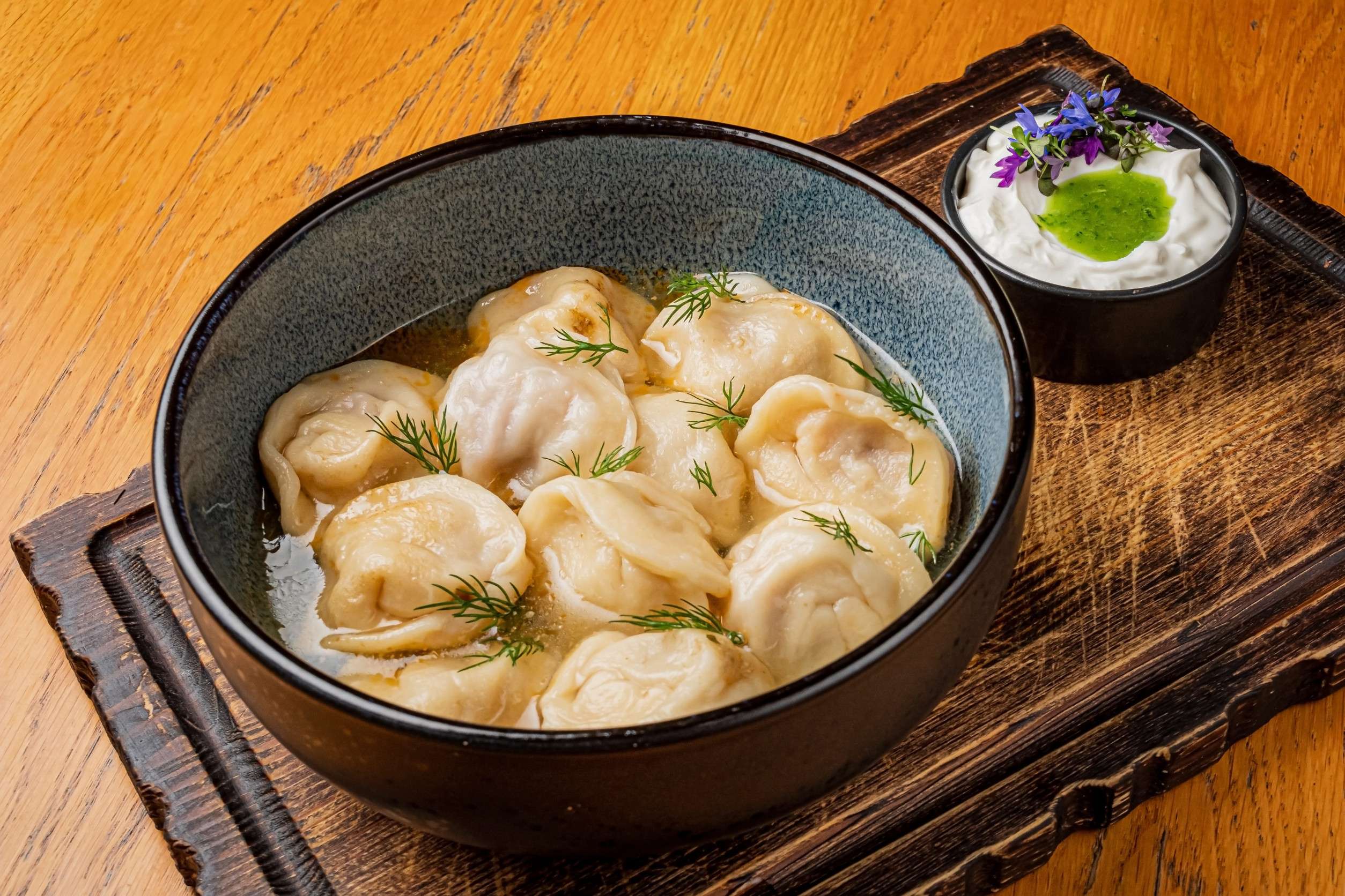 Pelmeni with a flavoured dip on a serving tray