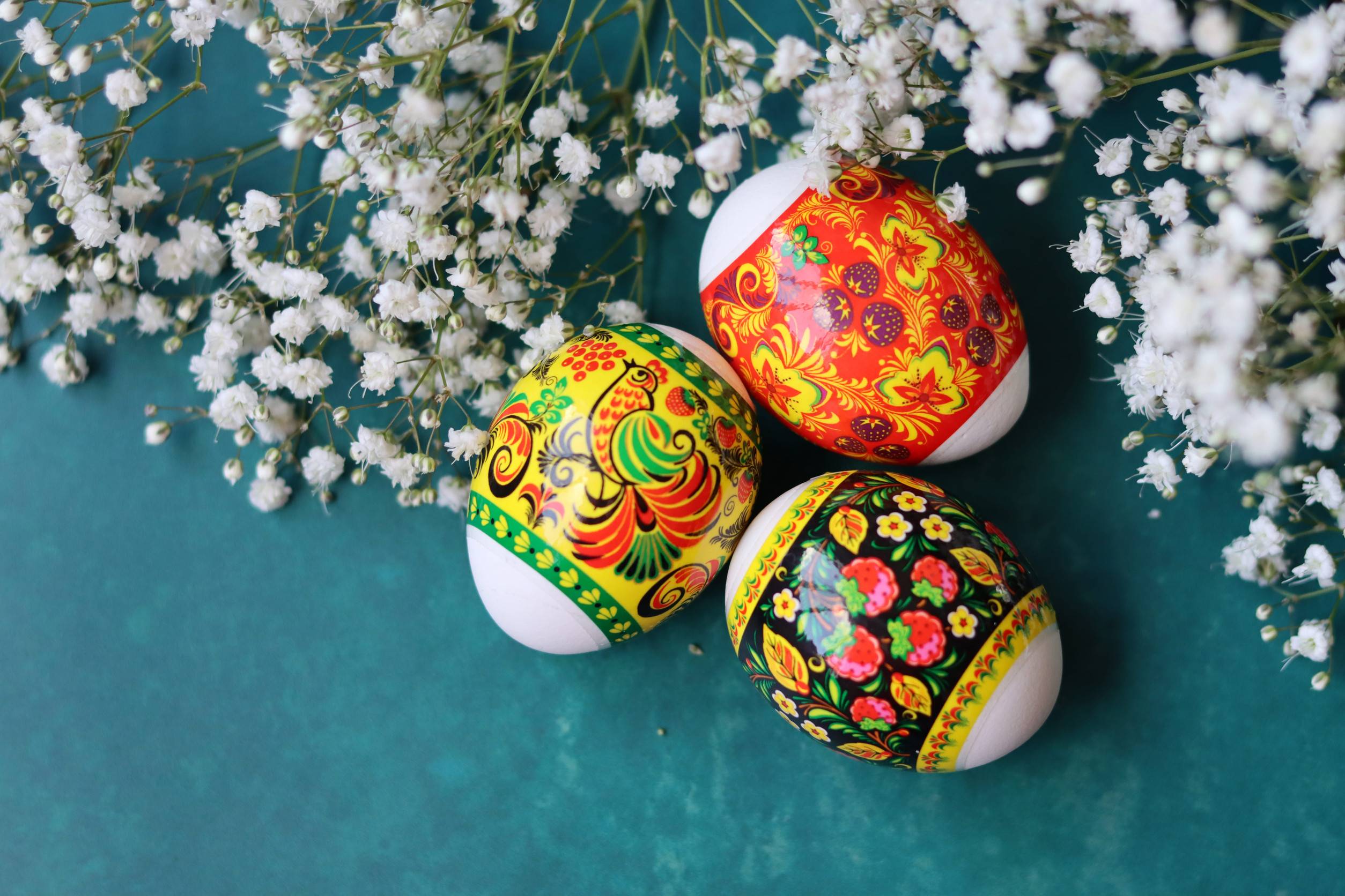 Some Easter Eggs that have been freshly coloured are lying next to some white flowers